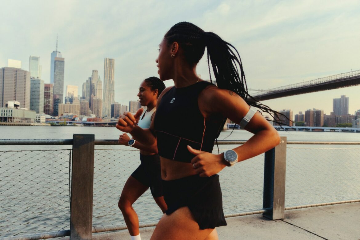 Two runners wearing COROS sports watches beside the New York waterfront